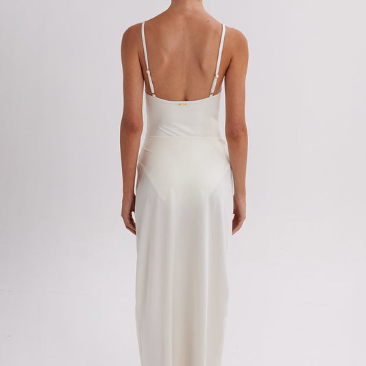 Woman wearing a white slip dress on a plain background. Skirt available at EVAMAIA.