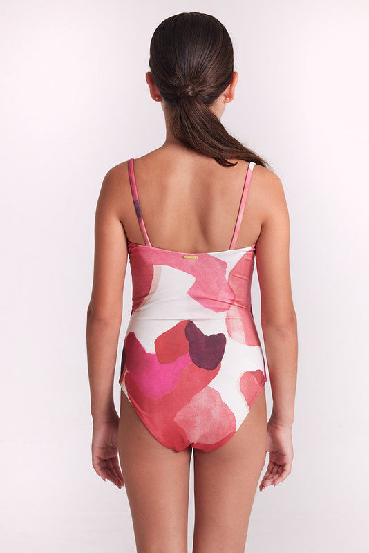 A girl wearing a one-piece swimsuit with a pink, red, and white abstract watercolor pattern against a plain white background.
