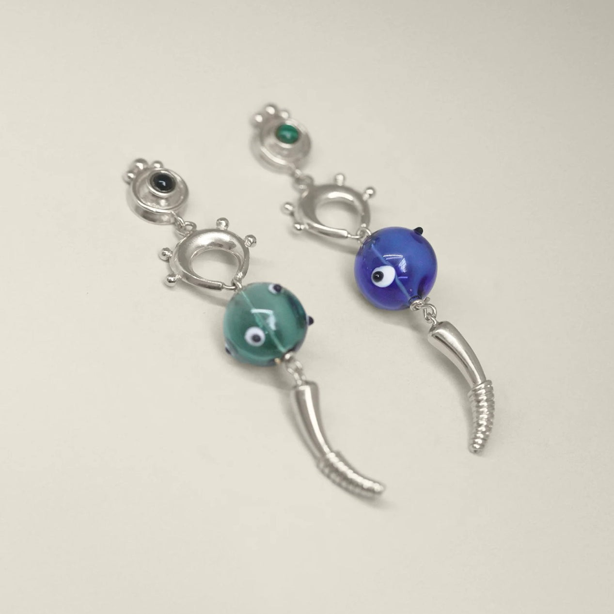 Pair of silver earrings with blue and green beads on a white bakcground.