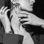 Black and white close-up of a woman wearing earrings with a hand adjusting them.