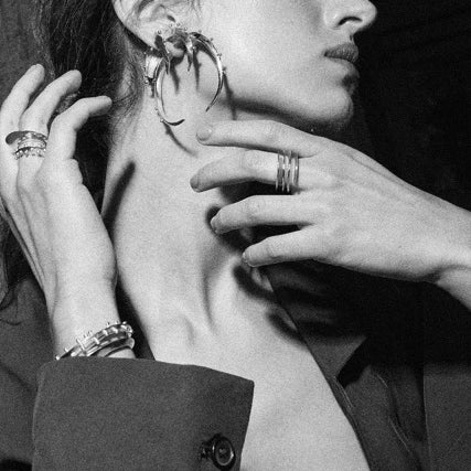 Black and white close-up of a woman wearing earrings with a hand adjusting them.