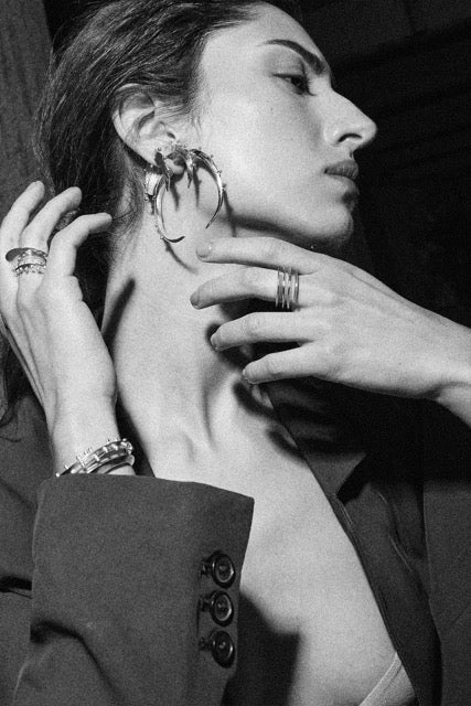 Black and white close-up of a woman wearing earrings with a hand adjusting them.