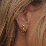 Gold seahorse earring worn by a person with blonde hair.