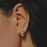 Gold leopard-shaped earring worn by a person with dark hair.