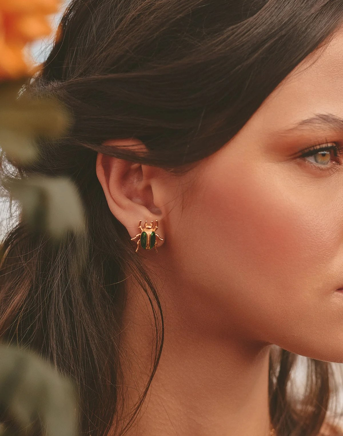 Close-up of a woman wearing earrings with a blurred natural background