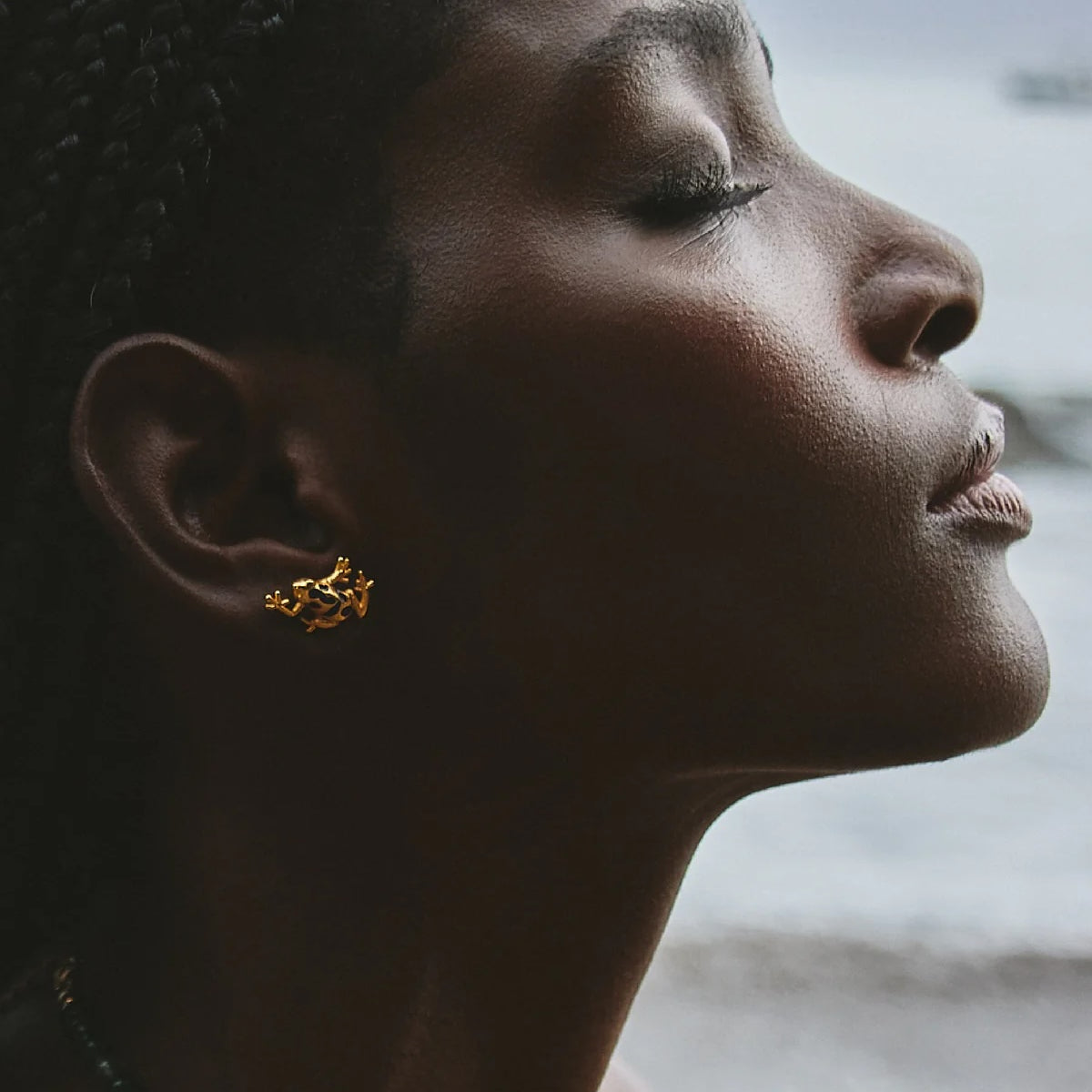 Close-up of gold plated brass frog earrings with blue detail, made in Medellín Colombia