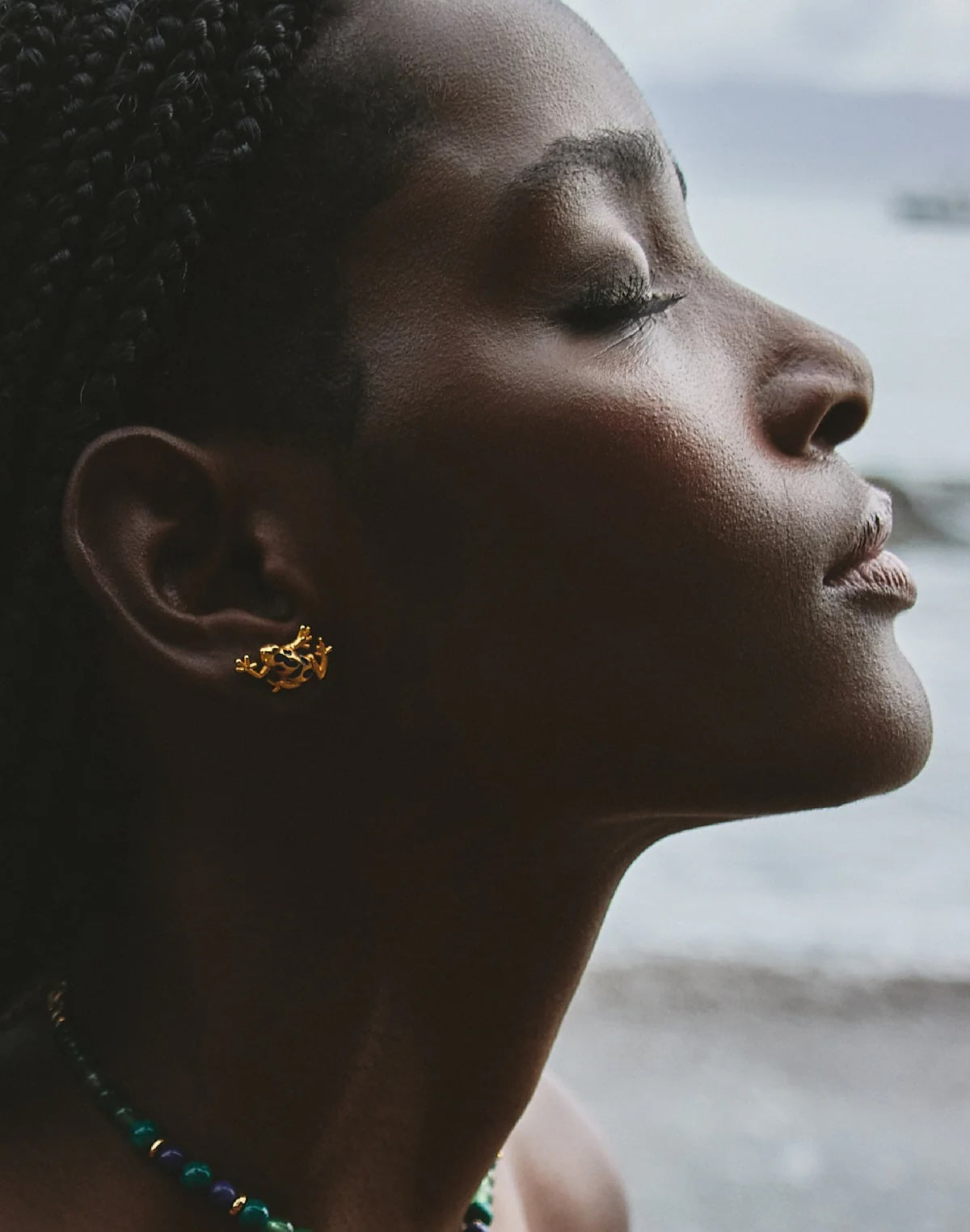 Close-up of gold plated brass frog earrings with blue detail, made in Medellín Colombia