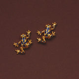 Gold plated blue enamel frog stud earrings on burgundy background