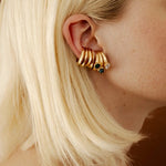 Gold earring cuffs with stones worn by a person with blonde hair.