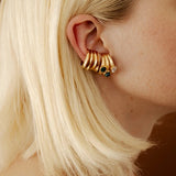 Gold earring cuffs with stones worn by a person with blonde hair.