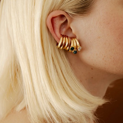 Gold earring cuffs with stones worn by a person with blonde hair.