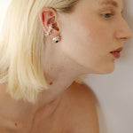 Close-up of a woman wearing silver earrings with a plain background.