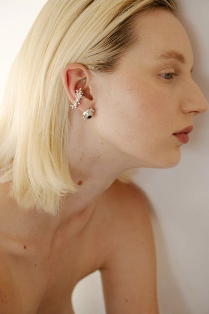 Close-up of a woman wearing silver earrings with a plain background.
