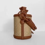 Small woven basket with brown leather straps and knot on a white background.