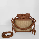 Brown woven bucket bag with leather accents on a white background.