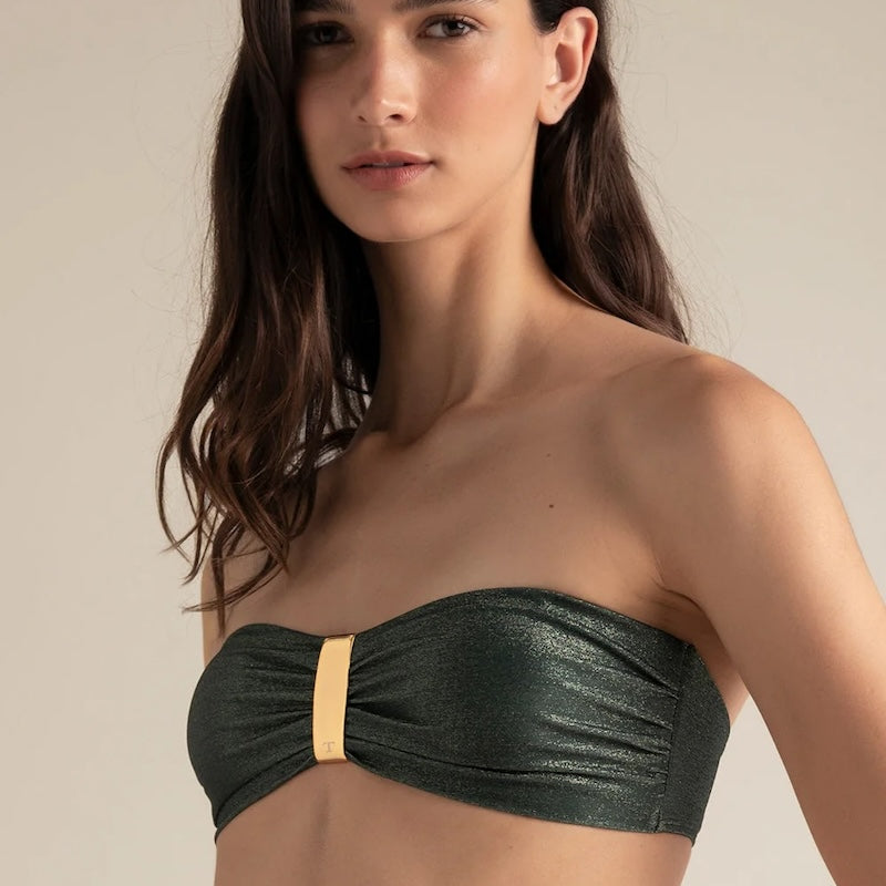 Woman wearing a green strapless bikini top against a neutral background.
