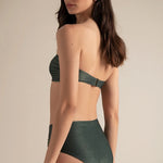 Woman wearing a green bikini against a beige background.