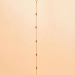 Gold plated lariat necklace on a beige background