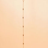 Gold plated lariat necklace on a beige background