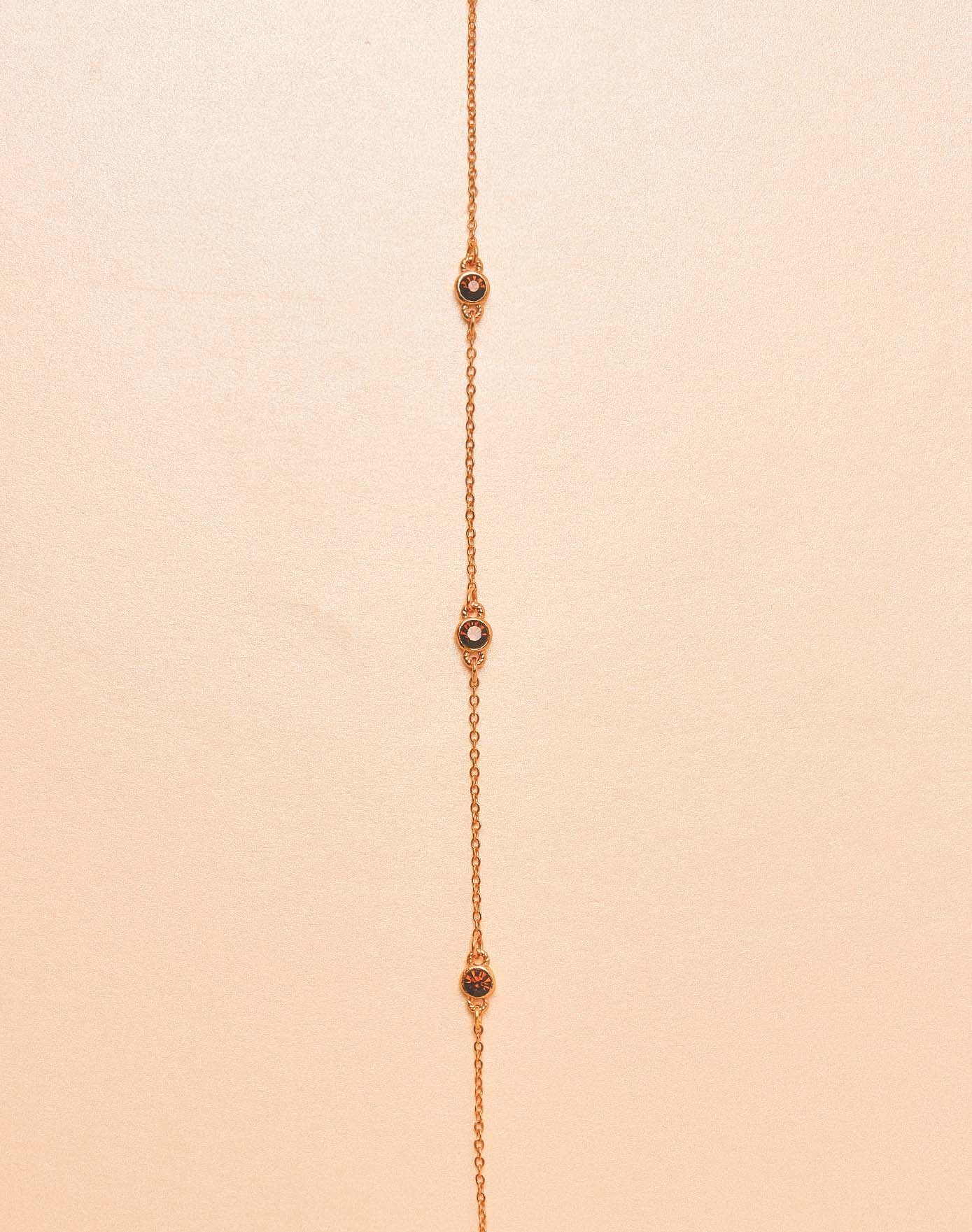 24k gold-plated necklace with small stones on a beige background