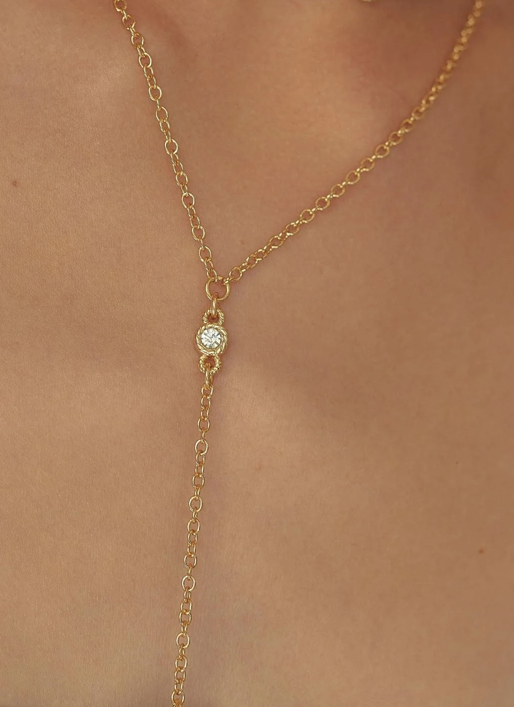 Gold necklace with a small gemstone on a person's neck
