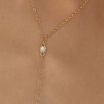 Gold necklace with a small gemstone on a person's neck