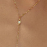 Gold necklace with a small gemstone on a person's neck