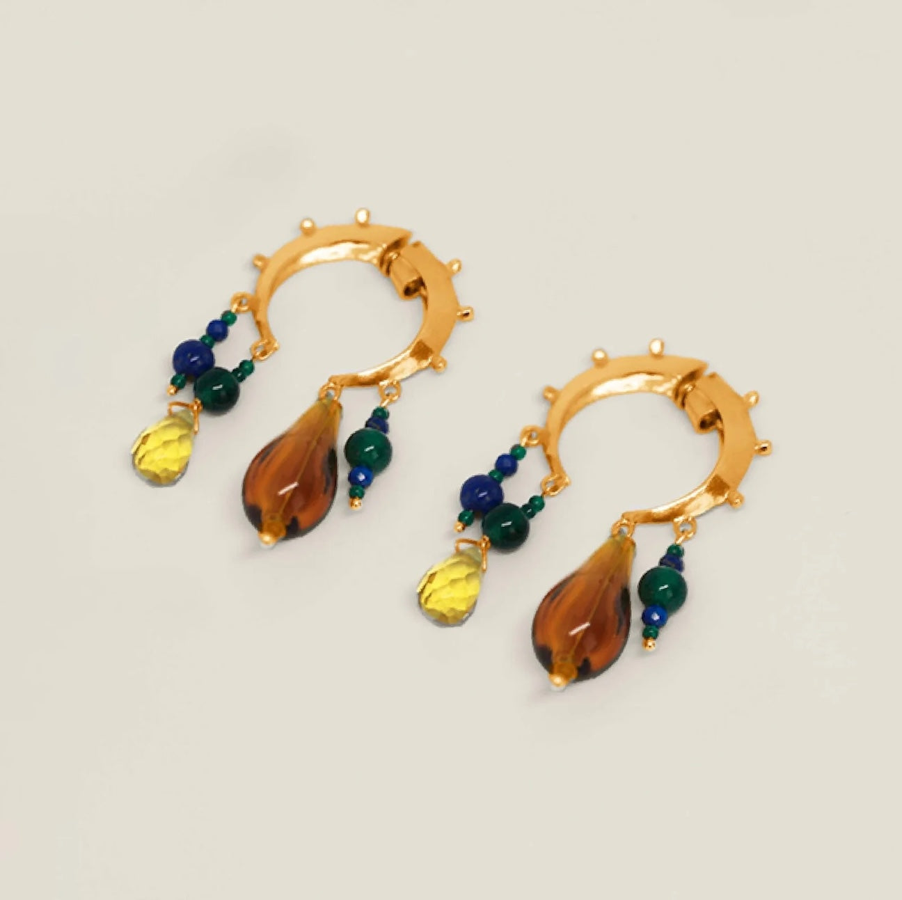 Pair of gold hoop earrings with colorful teardrop-shaped beads on a white background.