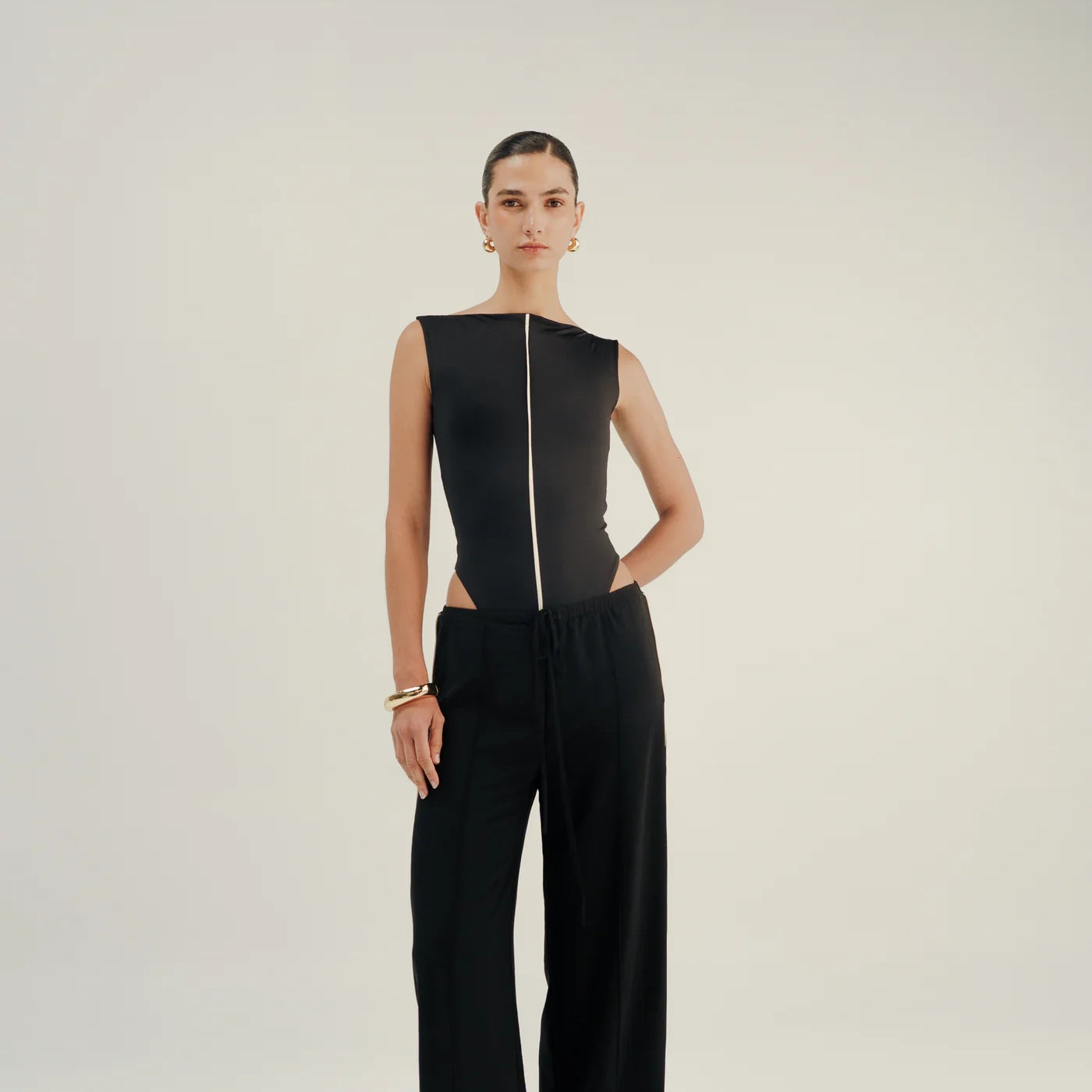 Person wearing a black bodysuit and wide-leg pants on a white background.
