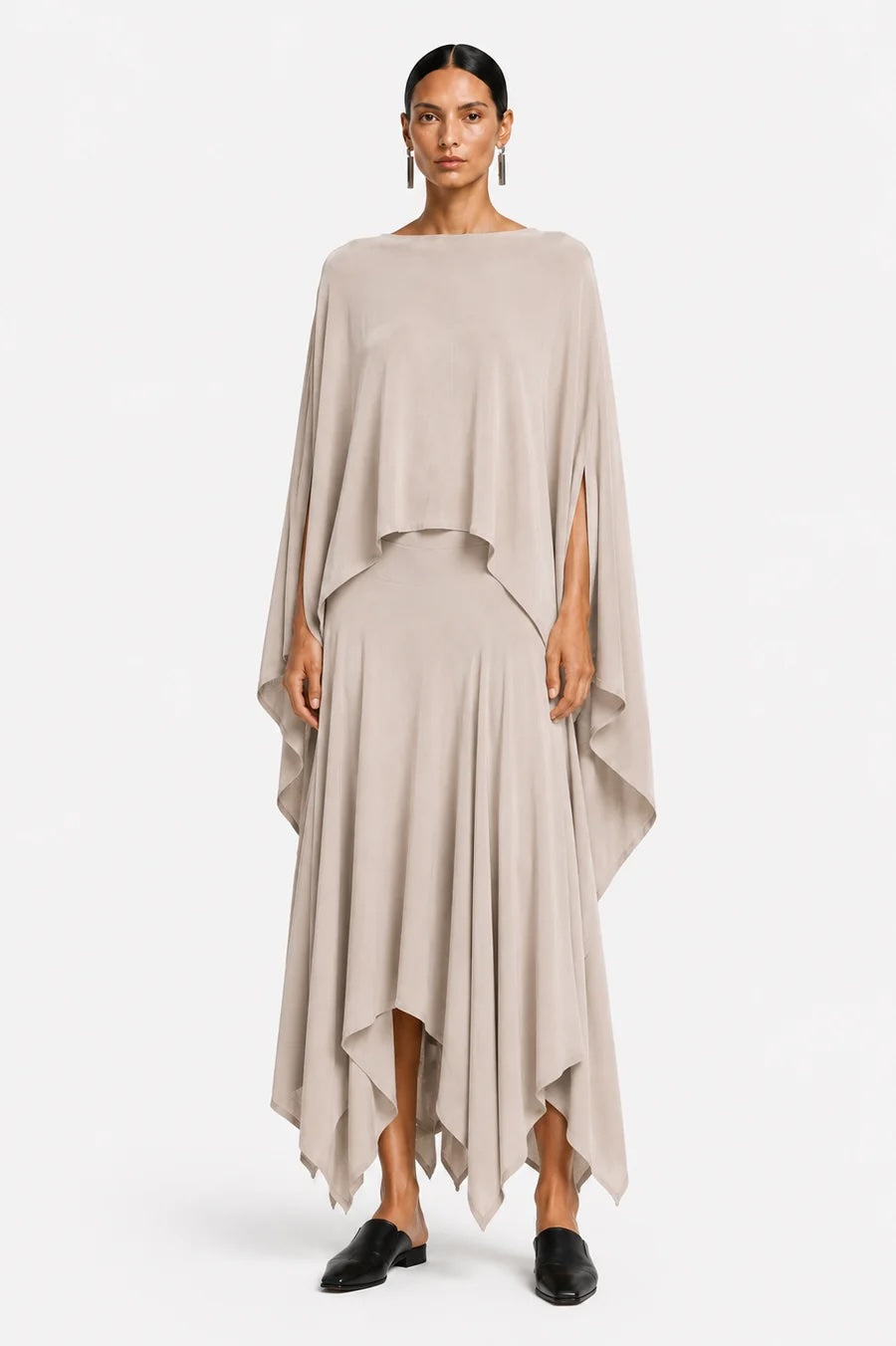 Woman wearing a beige one shoulder blouse over a layered skirt on a white background