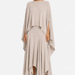Woman wearing a beige one shoulder blouse over a layered skirt on a white background