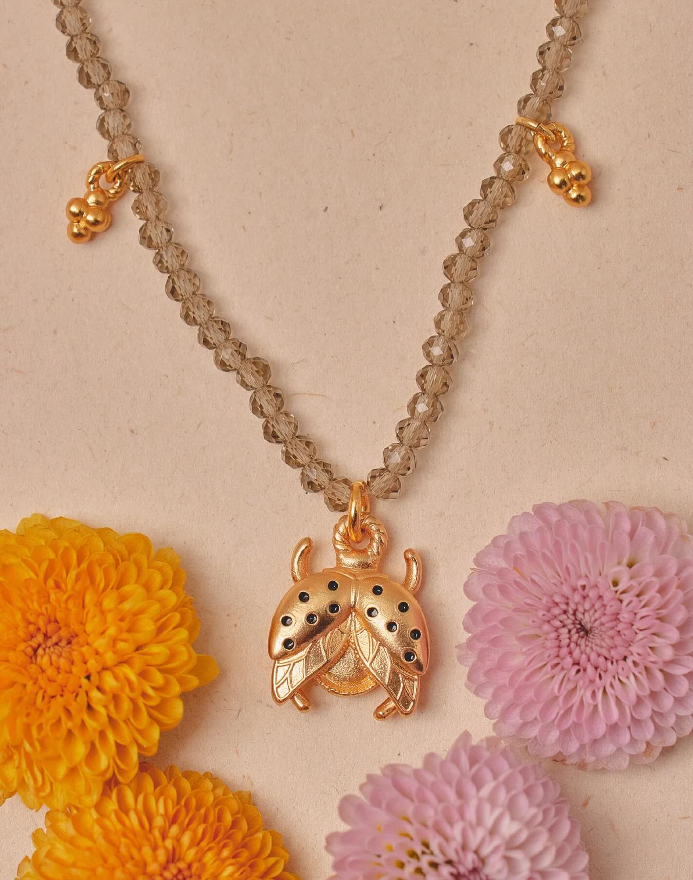 Necklace with a gold pendant on a beige background with flowers