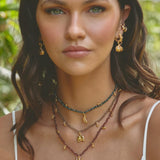 Woman wearing layered necklaces and earrings with a natural background