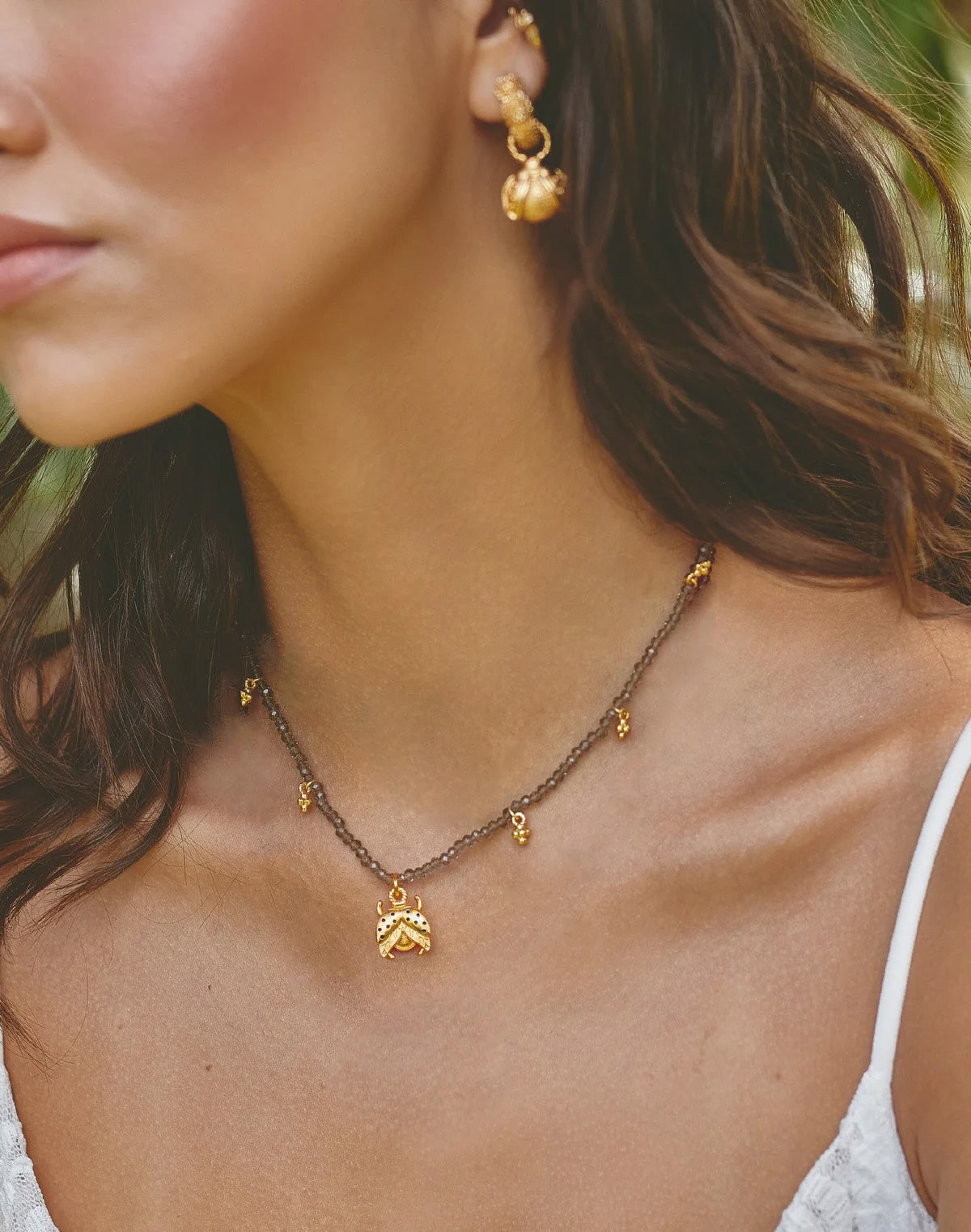Close-up of a woman wearing gold earrings and necklace with a blurred background