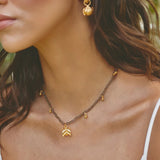 Close-up of a woman wearing gold earrings and necklace with a blurred background