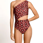 Red and black patterned one-shoulder swimsuit on a model against a white background
