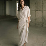 Woman wearing a white top and white skirt outfit in an industrial setting.