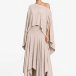 Woman wearing a beige one-shoulder blouse and layered skirt on a white background.