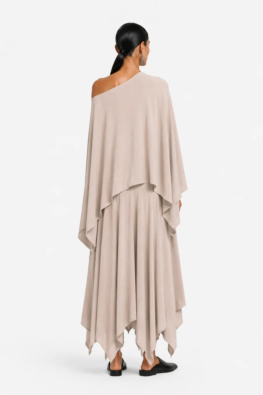 Woman wearing a beige one-shoulder blouse and a layered skirt on a white background