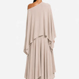 Woman wearing a beige one-shoulder blouse and a layered skirt on a white background