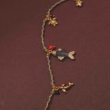 Necklace with fish and turtle charms on a brown background