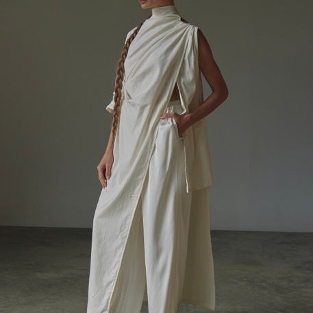 Woman wearing a flowing white outfit against a plain background.