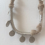 Necklace with silver coins and braided design on a white background