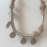 Necklace with silver coins and braided design on a white background