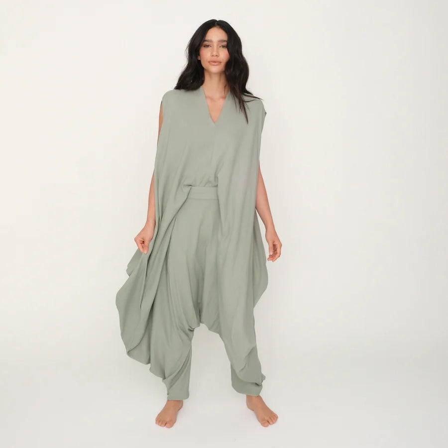 Woman wearing a green flowy jumpsuit against a white background.