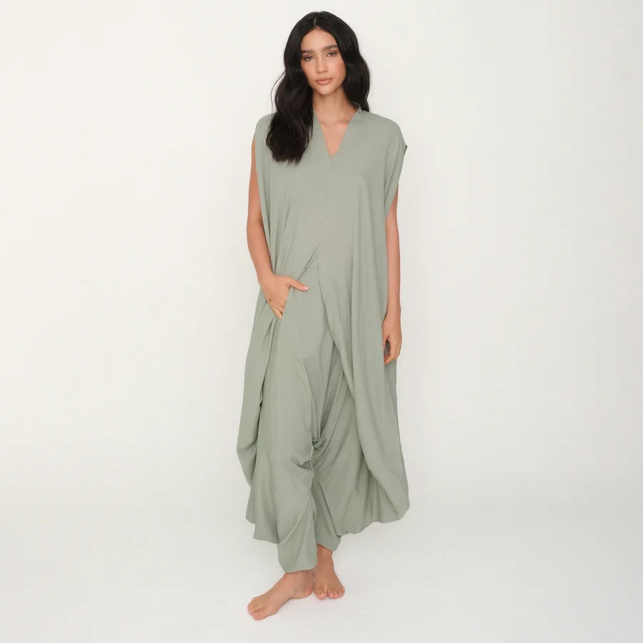 Woman wearing a light green jumpsuit on a white background.