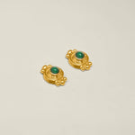 Pair of gold earrings with green gemstones on a white background.
