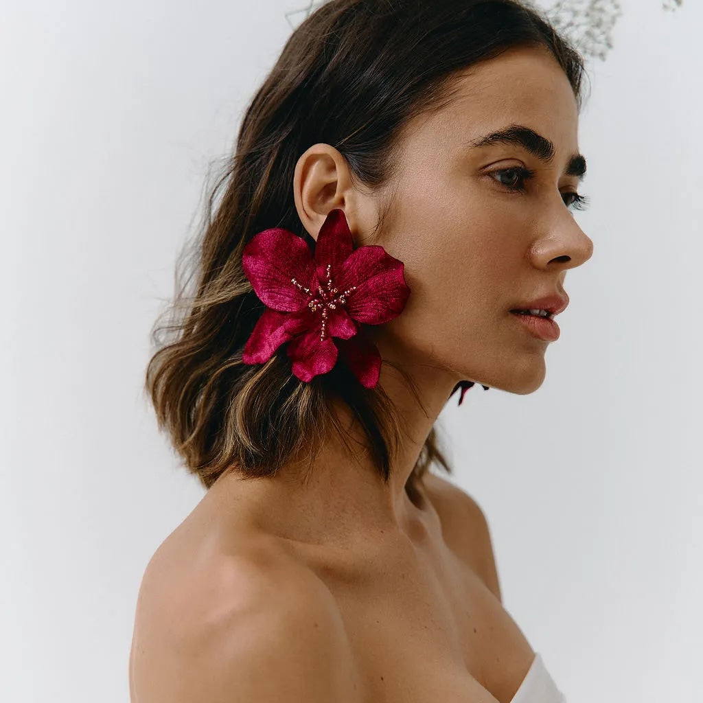 Woman wearing a bright pink flower earring against a white background