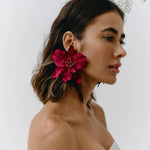 Woman wearing a bright pink flower earring against a white background