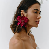 Woman wearing a bright pink flower earring against a white background